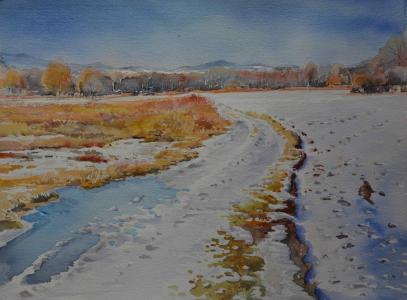 Zdjęcie przedstawiające pejzaż w okresie jesienno-zimowym. W tle drzewa, na pierwszym planie duża przestrzeń pokryta śniegiem. Obraz w kolorach biało-pomarańczowych.