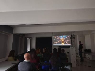 Górna sala Starej Fabryki. Uczestnicy przed ekranem telewizyjnym oglądają prezentację.