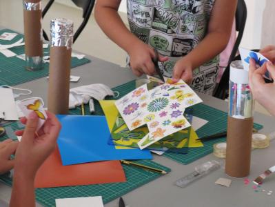 Warsztaty - dzieci wycunają z papieru kolorowe kwiaty i motyle.