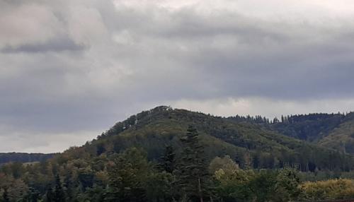 Zalesiona góra, nad nią pochmurne niebo.
