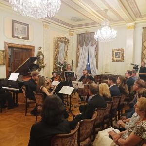 W sali wypełnionej publicznością, na pierwszym planie, w centrum uwagi znajduje się grupa pięciu muzyków, którzy oddają się swojej grze. Wśród nich wyróżnia się fortepian, który stanowi główny punkt tej artystycznej prezentacji. Zgromadzona publiczność uw