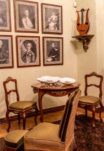 Sciana z portretami. Przy ścianie stolik z dwoma krzesłami oraz fotel.