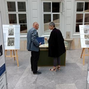 na środku zdjęcia Dyrektor Marek Matlak, po prawej stronie kobieta. - są zwróceni do siebie, rozmawiają, obok nich plakaty na drewnianych sztalugach, w tle Atrium