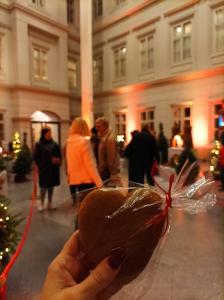 Ręka trzymająca piernik. W tle zwiedzający wystawę