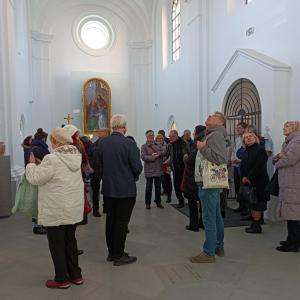 grupa ludzi znajdująca się we wnętrzu kaplicy zamkowej - podziwiająca zabytek, na pierwszym planie- po prawej stronie zdjęcia - mężczyzna w średnim wieku, ubrany na szaro, patrzący na sufit kaplicy