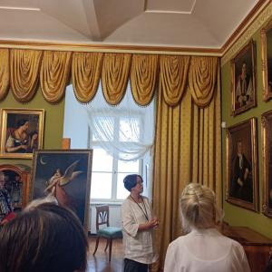 na środku zdjęcia P. Teresa Dudek Bujarek patrząca na obraz zawieszony na ścianie, w tle wnętrze ekpozycji Zamku