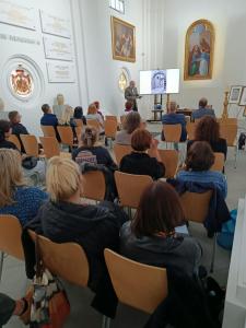 Cezary Kozak przedstawia sylwetkę artysty-grafika, Leona Wyczółkowskiego, w tle prezentacja slajdów z pracami artysty