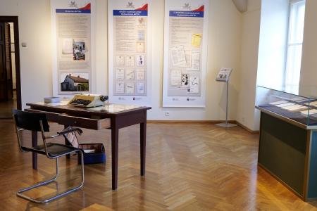 Fragment wystawy - po lewej biurko z maszyną do pisania, przed biurkiem krzesło, po prawej gablota.